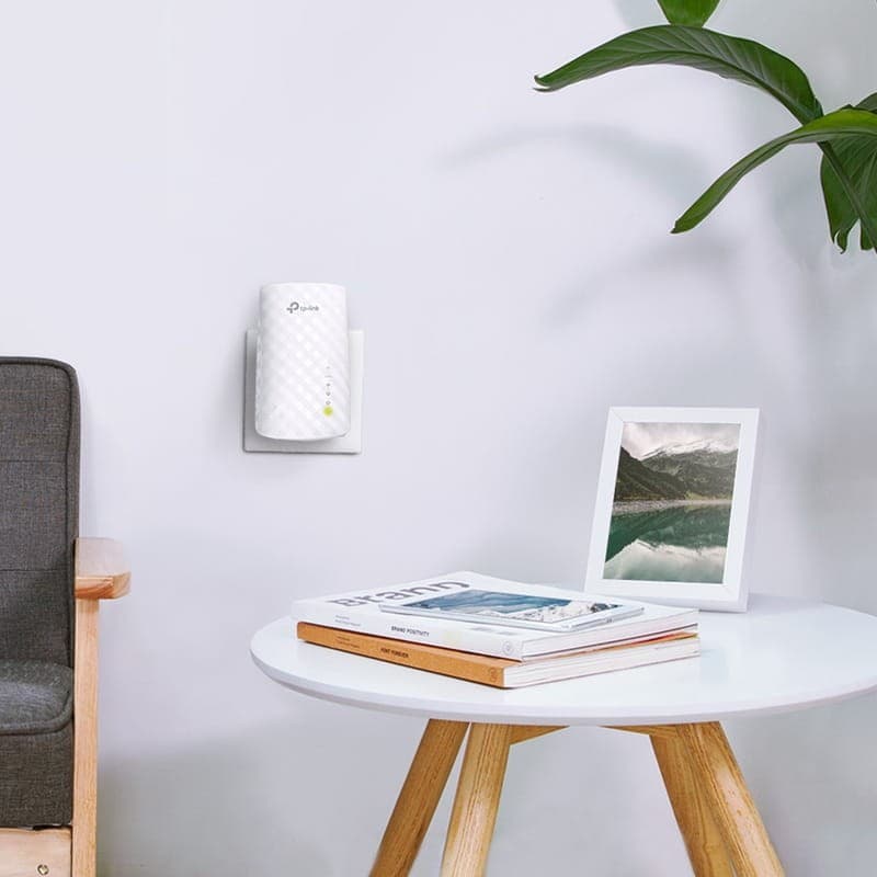 TP-Link RE200 AC750 repetidor Wi-Fi branco com textura xadrez, luzes LED de status e antenas internas, plugado na tomada em ambiente minimalista