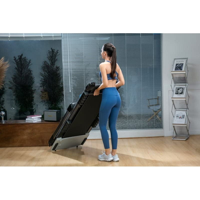 Cinta de Correr Plegable OVICX Q2S Plus - mujer sujetando la cinta plegada en vertical