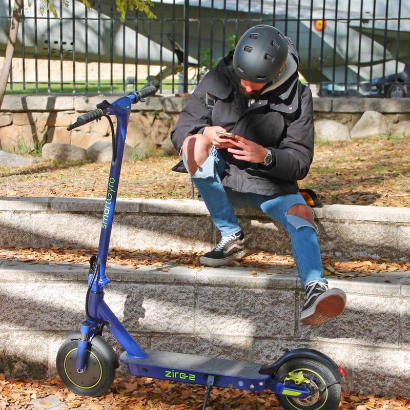 Patinete eléctrico con diseño innovador, junto a un conductor con el casco reglamentario