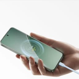 Mano sosteniendo smartphone cargándose con cable azul, mostrando animación de carga y porcentaje 16% sobre pantalla verde, borde metálico y cámara frontal
