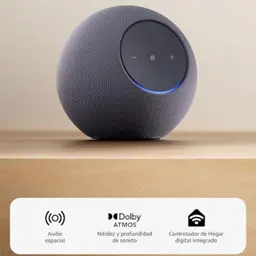 Amazon Echo Studio Grafito esférico con tela gris, panel superior táctil con botones y luz LED azul; base plana. Iconos indican audio espacial y Dolby Atmos