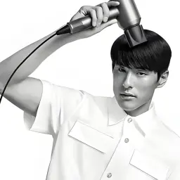 Sèche-cheveux Dyson Supersonic HD07 nickel cuivre tenu à la main, design compact en T, embout lissant noir en action sur cheveux courts, fini élégant