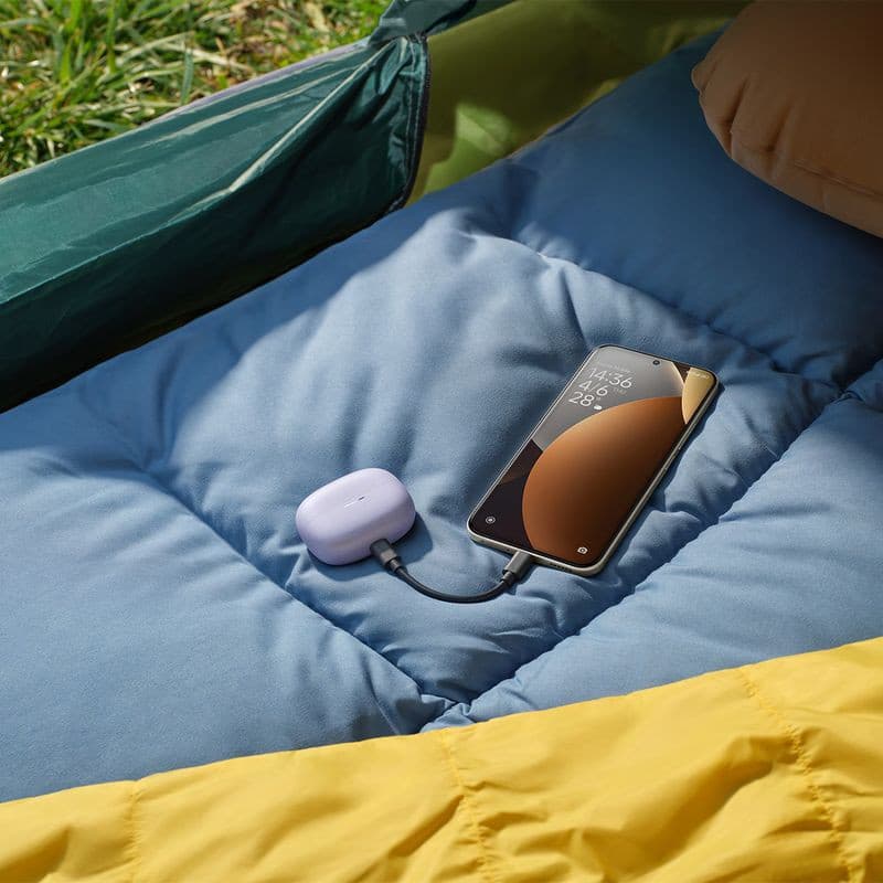 Xiaomi Redmi Note 15 Pro+ Bleu relié à un boîtier de charge violet sur un matelas de camping, écran lumineux bord fin, câble USB-C visible