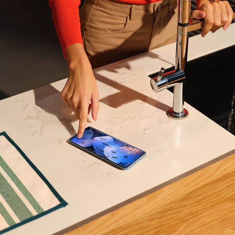 Xiaomi Redmi Note 15 5G púrpura con pantalla encendida sobre encimera mojada, resistente a salpicaduras; diseño fino y cámaras traseras múltiples
