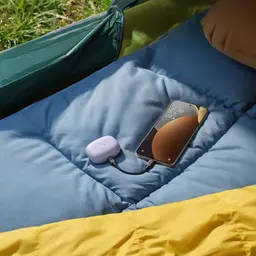 Xiaomi Redmi Note 15 Pro 5G 8GB/256GB Titânio em cama inflável azul, tela com relógio e cabo USB-C conectado a estojo lilás compacto de acessórios