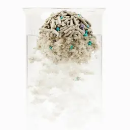 Granulado mixto para arena de gatos formando grumos compactos en agua, con partículas grises y azules, muestra alta absorción y disolución controlada Pack x4
