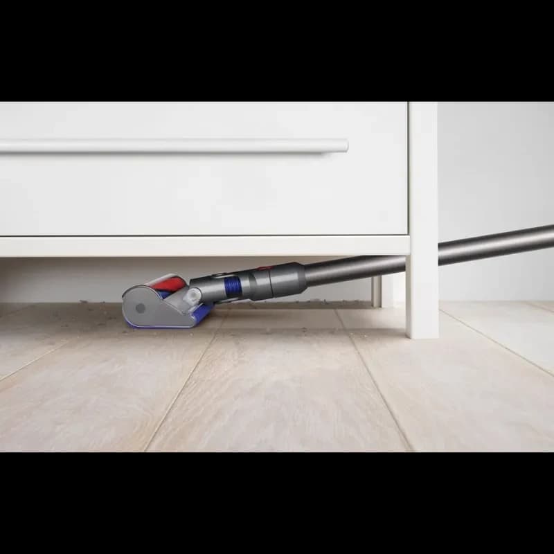 Cepillo motorizado de la Dyson V8 Cyclone limpiando bajo un mueble, diseño bajo perfil con rodillo suave y tubo delgado para acceder a espacios estrechos