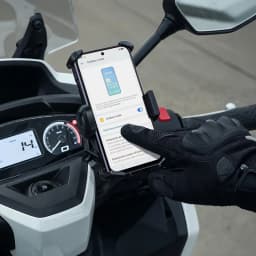 Oppo A6X 128GB Negro Lila montado en soporte para moto, pantalla 6.75 pulgadas visible al sol, funda protectora y guante táctil interactuando con el móvil