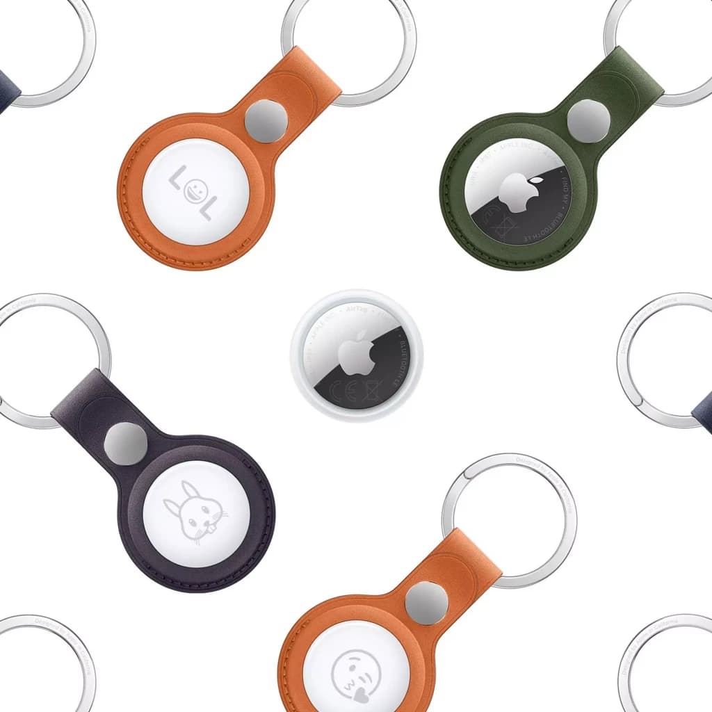Apple AirTag 2e génération rond blanc et noir, logo Apple central. Présenté avec porte-clés en cuir et silicone multicolores, accents métalliques