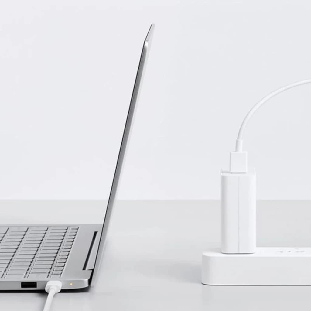 Carregador Xiaomi 100W Type-A EU branco conectado a régua de energia, cabo USB ligado, design compacto e minimalista ao lado de um laptop prateado