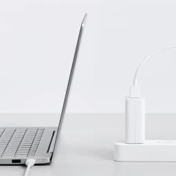 Carregador Xiaomi 100W Type-A EU branco conectado a régua de energia, cabo USB ligado, design compacto e minimalista ao lado de um laptop prateado