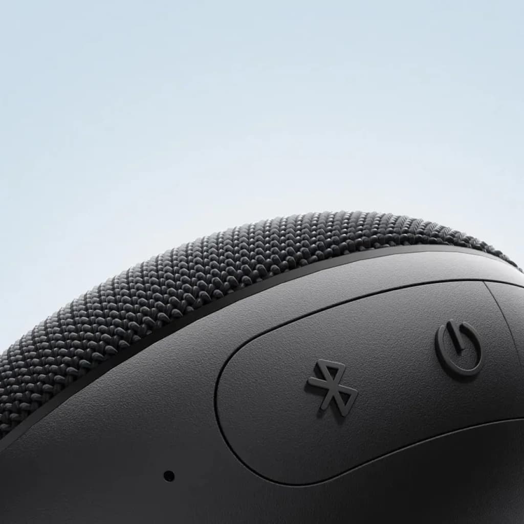 Gros plan sur enceinte portable noire Xiaomi: tissu maillé texturé, boutons Bluetooth et marche visibles, bords arrondis, design compact et moderne IP66