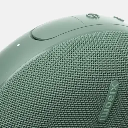 Grille textile vert sauge avec logo Xiaomi relief, bouton circulaire et LED. Finition arrondie antidérapante, détails soignés pour enceinte portable IP66.