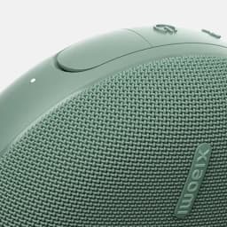 Enceinte portable verte avec tissu maillé, logo Xiaomi en relief, bouton circulaire et LED discrète, bords arrondis au fini mat, design compact et robuste
