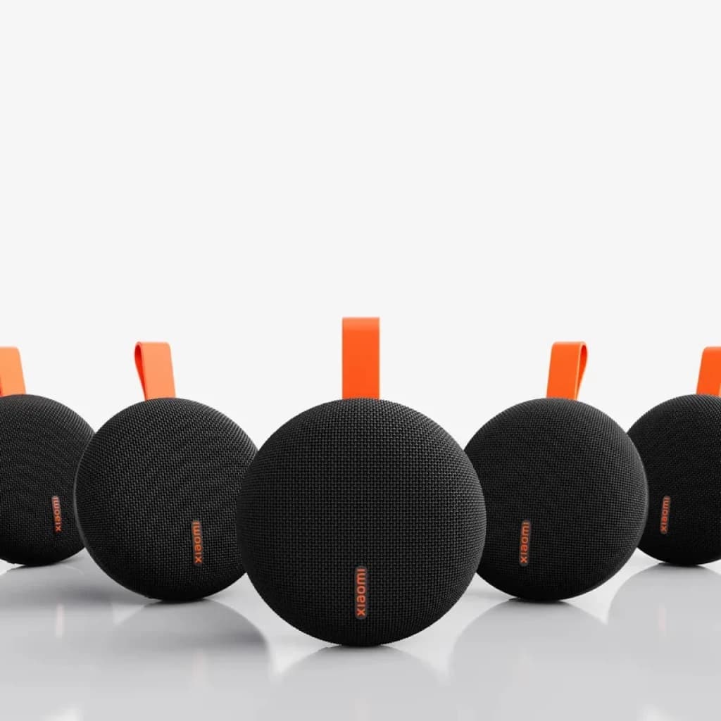 Xiaomi Bluetooth Speaker Essential 5W vert, boîtier rond noir maillé, logo orange, sangle de transport orange, design compact IP66, plusieurs unités