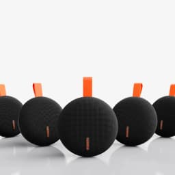Xiaomi Bluetooth Speaker Essential 5W vert, boîtier rond noir maillé, logo orange, sangle de transport orange, design compact IP66, plusieurs unités