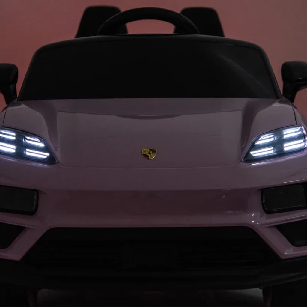 Porsche Macan Rosa infantil 12V licenciado, vista frontal com faróis LED acesos, grade lisa com emblema central e volante esportivo, controle parental 2.4G