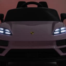 Porsche Macan Rosa infantil 12V licenciado, vista frontal com faróis LED acesos, grade lisa com emblema central e volante esportivo, controle parental 2.4G