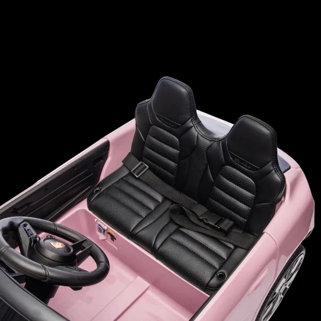Banco duplo em couro sintético preto com cinto de segurança, volante com emblema Porsche e painel detalhado em carro elétrico infantil rosa 12V