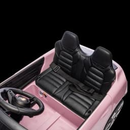 Banco duplo em couro sintético preto com cinto de segurança, volante com emblema Porsche e painel detalhado em carro elétrico infantil rosa 12V