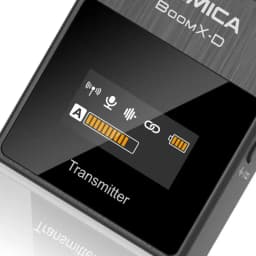 Émetteur Comica BoomX-D D1 Noir gros plan avec écran OLED: icônes signal, micro, lien, niveau A et batterie, boîtier noir brossé mention Transmitter