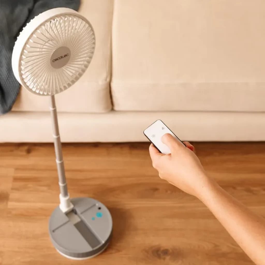Ventilateur sur pied pliable gris avec télécommande, tête ronde à pales fines, mât télescopique et base stable à boutons bleus, design compact et