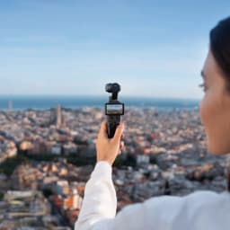 DJI Osmo Pocket 4 Standard Edition 4K 120fps con gimbal de 3 ejes, pantalla integrada mostrando paisaje urbano, diseño compacto en mano para video estable