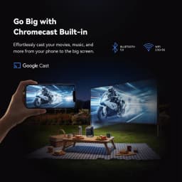 Projetor portátil Wanbo ToGo Pro 1080p, 500 ANSI lúmens, corpo compacto com alça, lente frontal grande; exibe filme ao ar livre com conexão Wi‑Fi e