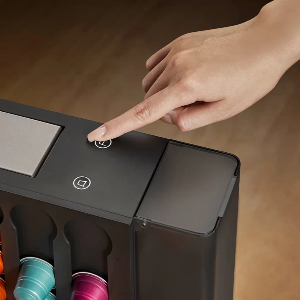 Bouton tactile d’extraction sur la Machine à café à capsules Xiaomi Mijia, interface minimaliste, rangée de capsules colorées visible, finition noire