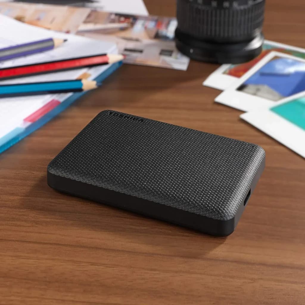 Disque dur externe Toshiba Canvio Advance 2To USB 3.2 Gen 1 Noir, en situation: posé sur bureau en bois avec crayons
