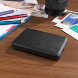 Disque dur externe Toshiba Canvio Advance 2To USB 3.2 Gen 1 Noir, en situation: posé sur bureau en bois avec crayons
