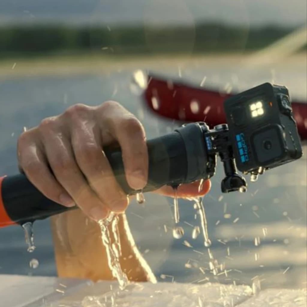 GoPro Lit Hero 4K 60fps 12 MP, sumergible 5 m con HyperSmooth, montada en tubo de agarre; carcasa negra, LEDs frontales encendidos y gotas de agua en acción
