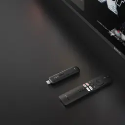 Clé HDMI compacte noire avec télécommande Xiaomi, boutons Netflix YouTube Prime Video et Assistant Google, design minimaliste près d’un téléviseur