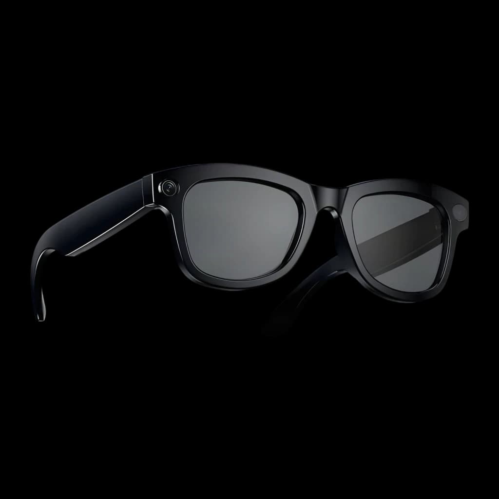 Lunettes noires brillantes à monture épaisse, verres fumés rectangulaires, bouton latéral discret, branches larges intégrant caméra et audio open-ear