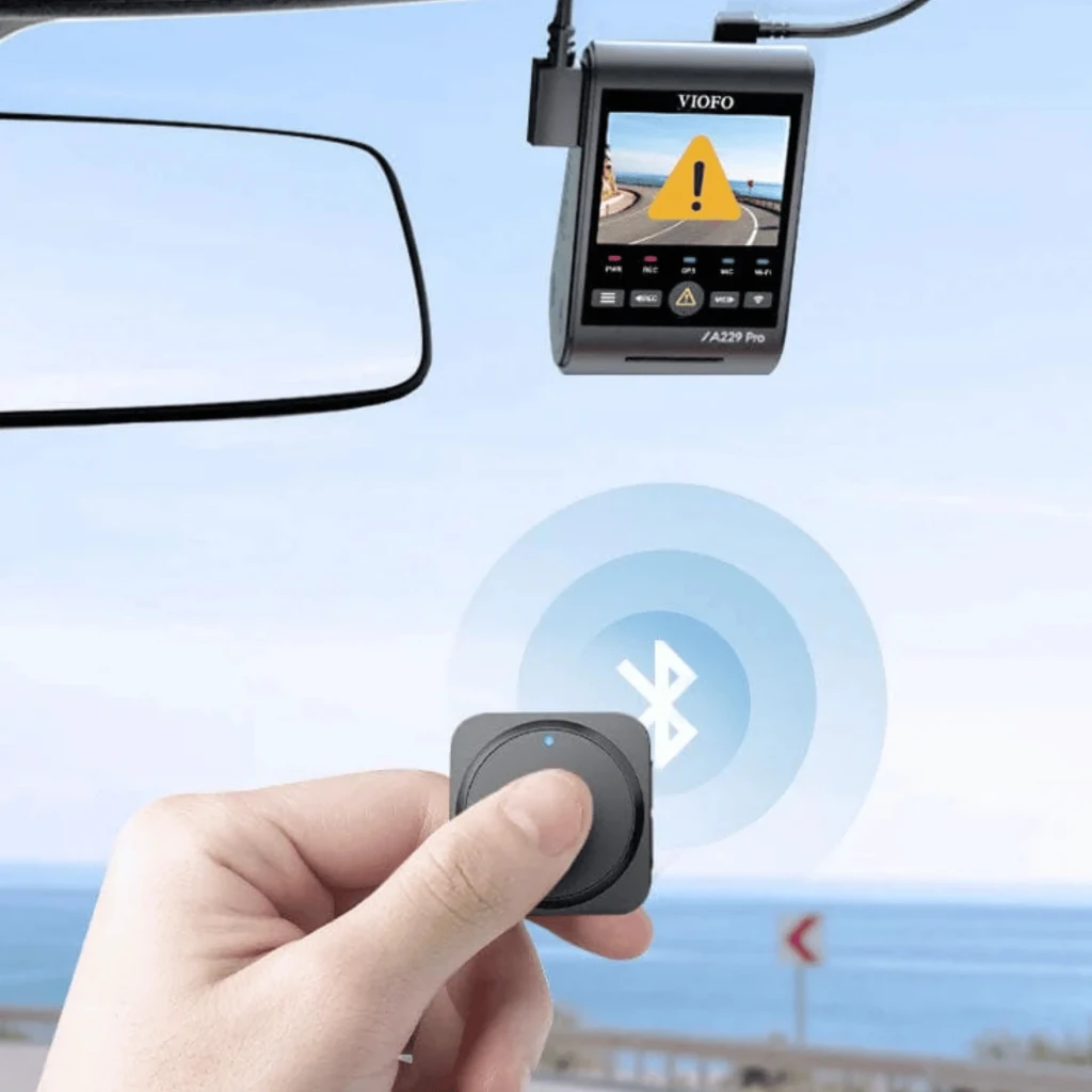 VIOFO BTR200 Télécommande Bluetooth compacte en noir, boîtier carré arrondi avec grand bouton circulaire et triangle lumineux jaune, LED d’état discrète - Ítem3