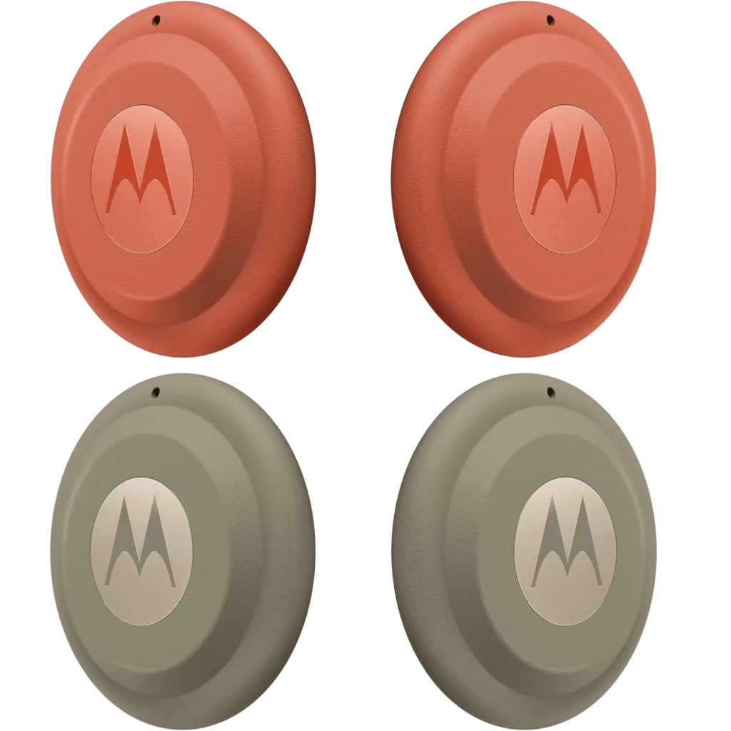 Moto Tag 2.0 da Motorola em formato circular, acabamento fosco, disponível em laranja e cinza, com logo M central em relevo e pequeno furo superior - Item