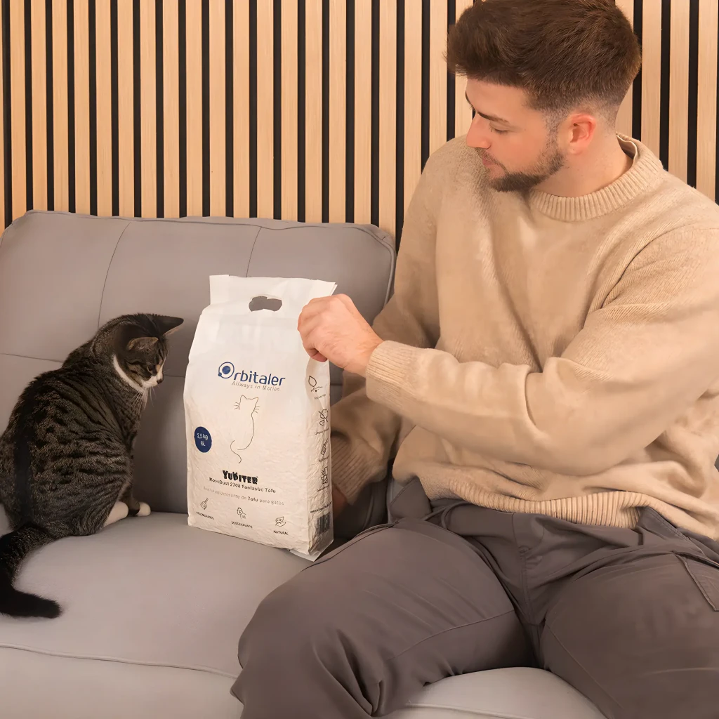 Arena para gatos Orbitaler Yupiter MoonDust 2700 Fantastic Tofu, pellets blancos finos, absorción alta, caja 2.5 kg con asa azul y gato gris al lado - Ítem2