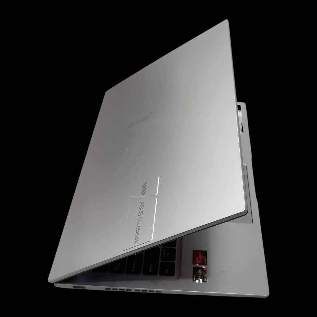 ASUS Vivobook 15 M1502YA 512GB Plata, vista inferior en ángulo: tapa trasera plateada, bisagra y stickers AMD Ryzen visibles