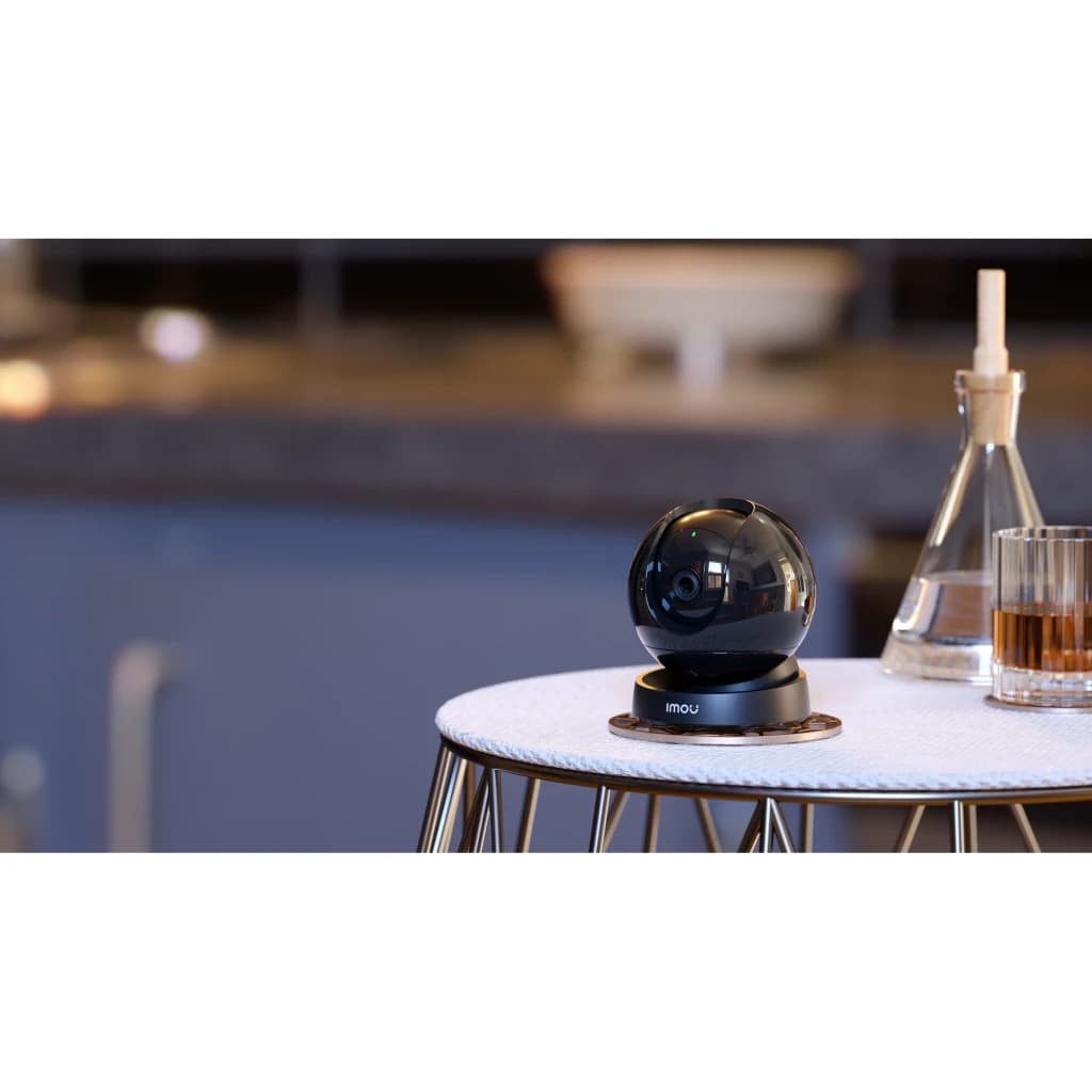 Imou Rex 3D 2K 256GB Negro, vista ambiental: cámara esférica negra sobre mesa redonda en interior con fondo desenfocado