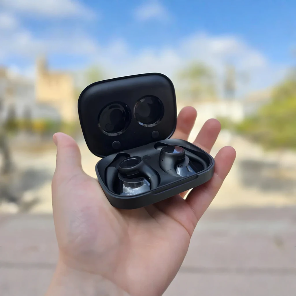 Écouteurs open-ear noirs avec contour d oreille, boîtier de charge compact, design mat, commandes tactiles et ports magnétiques visibles - Ítem4