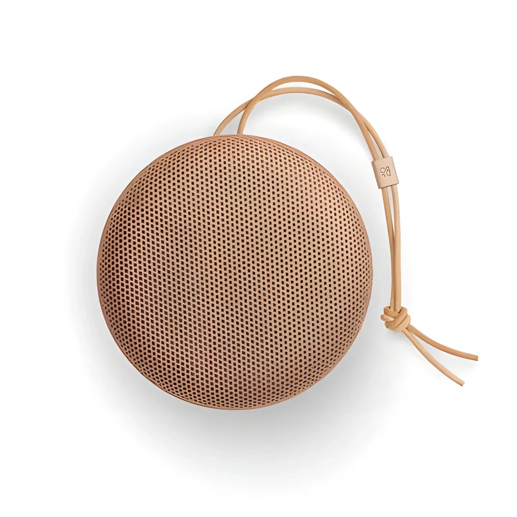 Bang & Olufsen Beosound A1 3rd Gen Honey Tone, vue en angle: forme circulaire, grille perforée et lanière en cuir avec logo - Ítem2