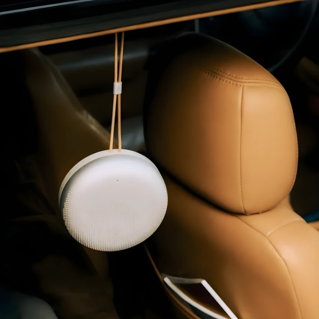 Bang & Olufsen Beosound A1 3rd Gen Honey Tone, vue en angle: forme circulaire, grille perforée et lanière en cuir avec logo - Ítem5