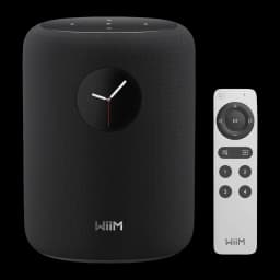 Wiim Sound negro, vista frontal: altavoz cilíndrico con pantalla de reloj analógico y mando a distancia blanco incluido