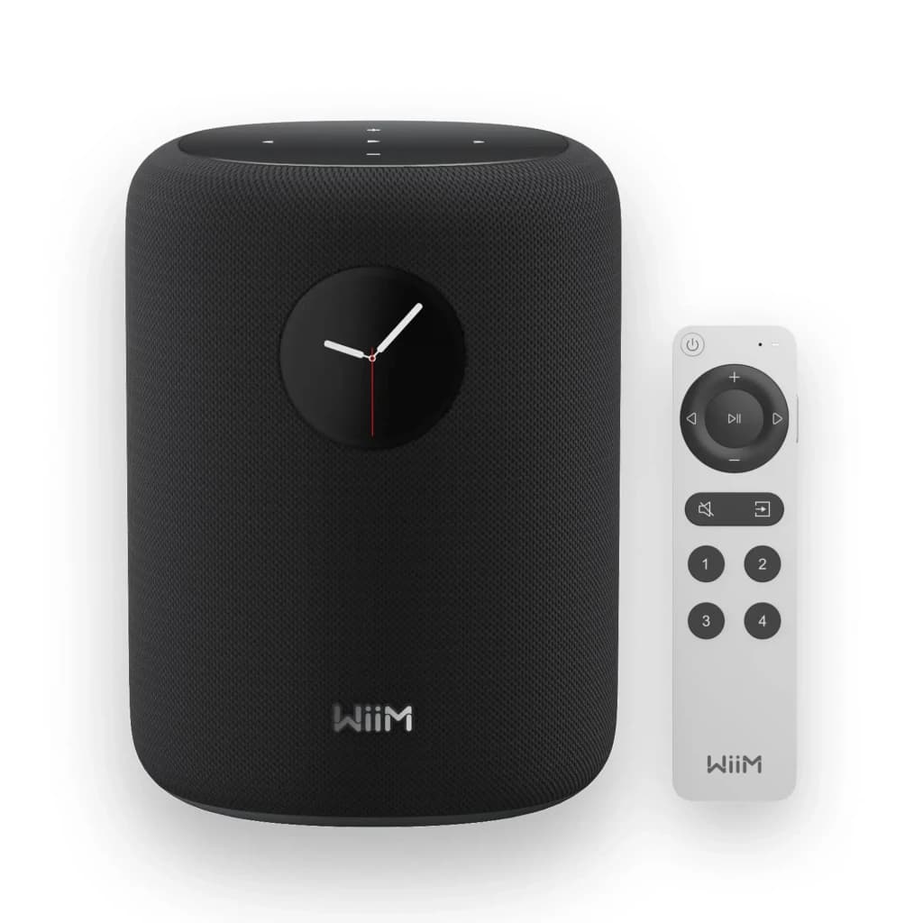 Wiim Sound negro, vista frontal con mando: altavoz negro con reloj analógico y mando a distancia blanco incluido