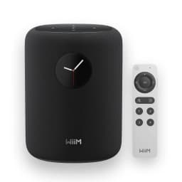 Wiim Sound negro, vista frontal con mando: altavoz negro con reloj analógico y mando a distancia blanco incluido