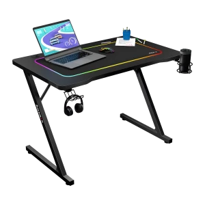 Huzaro Bureau gaming Hero 1.8 Noir, vue en perspective: éclairage RGB sur le bord, pieds en Z, laptop, souris, casque et