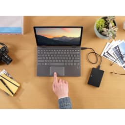 Seagate Expansion STKN1000400 1TB negro, vista cenital: disco conectado por USB a laptop sobre escritorio de madera