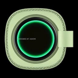 Altavoz portátil verde con aro LED luminoso, diseño cuadrado con bordes redondeados y correa lateral; textura trenzada alrededor del marco