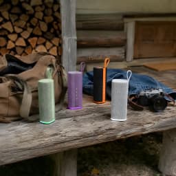Altavoz cilíndrico púrpura con asa, malla textil y base luminosa violeta; botones frontales verticales y diseño portátil resistente IP68
