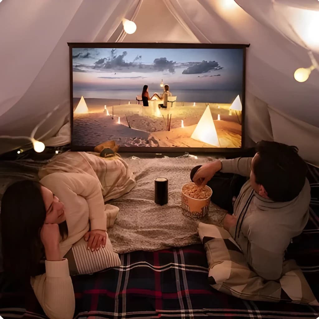 Proyector XGIMI Halo+ GTV compacto en carpa, proyecta escena nítida Full HD; cuerpo cilíndrico negro junto a espectadores, luces cálidas y pantalla portátil